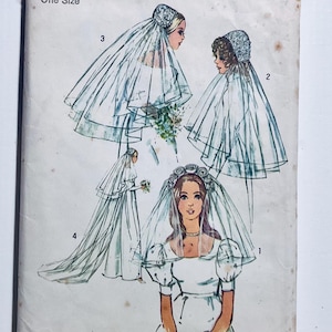 May include: Vintage sewing pattern with illustrations of brides in wedding veils and gowns. The drawings show different veil styles, including lace-trimmed and draped designs, and bridal gown silhouettes. The pattern is labelled "One Size".