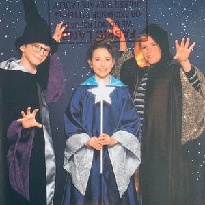 Pode incluir: Três crianças vestidas com fantasias de bruxo posam contra um fundo estrelado. Uma usa um chapéu e capa pretos com detalhes roxos, outra um robe azul com uma varinha de estrela, e a terceira uma capa com capuz preta com detalhes dourados. A imagem é de um padrão.