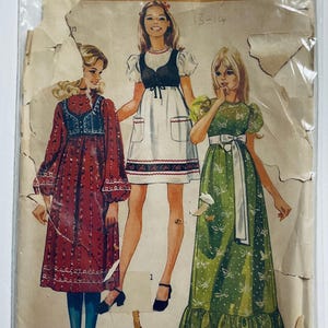 Cute dress with high round neckline and either short very puffy sleeves or set in sleeves with puffy gathers at wrist. Gathered high waist and optional gathered lower skirt band. Patch pockets, trim and lined bolero.