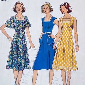 Puede incluir: Patrón de costura vintage con tres diseños de vestidos. Un vestido es de color turquesa con estampado floral, otro es azul liso y el tercero es amarillo con un patrón blanco. Cada vestido tiene un escote cuadrado y una cintura entallada.