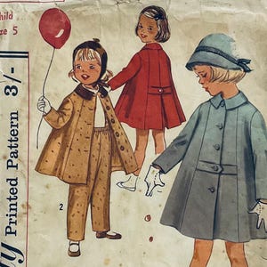 Può includere: Modello di cucito vintage per un cappotto per bambini. Il modello è per la taglia 5 ed è un modello stampato. Il modello mostra tre ragazze che indossano cappotti diversi. Una ragazza indossa un cappotto rosso, un'altra indossa un cappotto marrone con un colletto bianco e la terza ragazza indossa un cappotto blu con un colletto bianco.