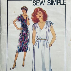 以下が含まれることがあります： 「SEW SIMPLE」と書かれたヴィンテージの裁縫パターン。2つのドレスのイラストが描かれています。1つは黒いベルトが付いたカラフルな抽象的なプリントで、もう1つはVネックと細いベルトが付いた白いドレスです。