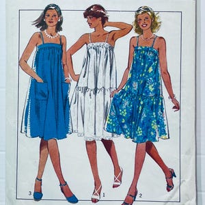 Peut inclure: Un patron de couture vintage présentant trois modèles de robes. Les robes comprennent une robe bleu uni avec des poches, une robe blanche avec une bordure en dentelle et une robe à imprimé floral bleu. Chaque robe a une encolure carrée et des bretelles spaghetti.
