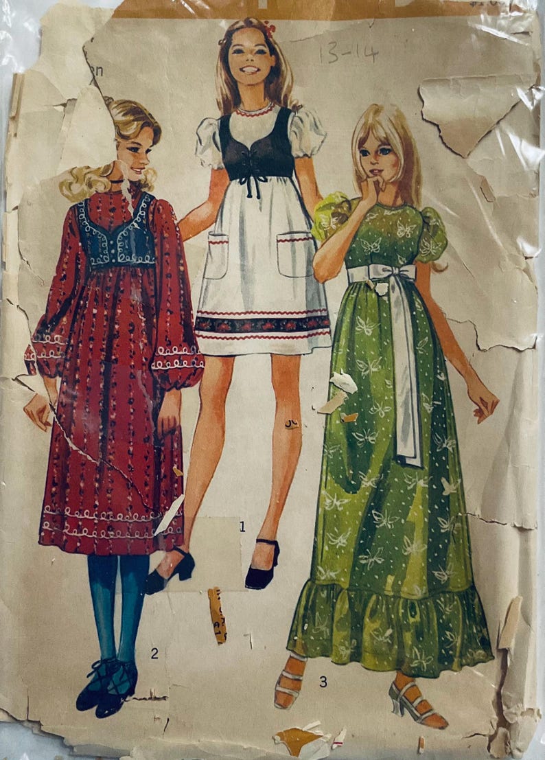 Cute dress with high round neckline and either short very puffy sleeves or set in sleeves with puffy gathers at wrist. Gathered high waist and optional gathered lower skirt band. Patch pockets, trim and lined bolero.