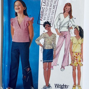 May include: A sewing pattern featuring illustrations of girls' clothing. The designs include a pink top with ruffled sleeves, a wrap top, a floral skirt, and striped pants. The pattern is from Wrights.