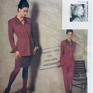 May include: Two women wearing red suits. The woman on the left is holding a sign that says "Purchased from the John Lewis Partnership".