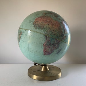 May include: A vintage globe with a green and brown map on a brass stand. The globe is tilted to show Africa.