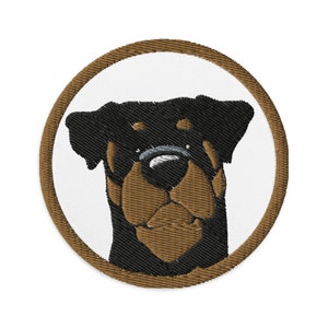 Puede incluir: Parche bordado de un perro Rottweiler con pelaje marrón y orejas negras, mirando al espectador con una expresión seria. El perro está rodeado de un círculo marrón.
