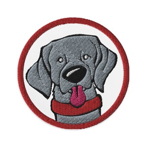 May include: Embroidered patch of a gray dog with a red collar and a pink tongue sticking out. The dog is in a circle with a red border.