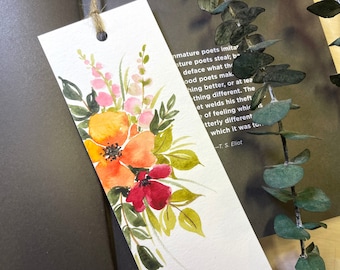 May include: A watercolor bookmark featuring a bouquet of flowers in shades of orange, pink, and red. The bookmark has a quote from T.S. Eliot: "Mature poets imitate; immature poets steal; bad poets deface what they steal, and good poets make something better, or at least something different. The good poet welds his theft and feeling into something utterly different from what it was to begin with."
