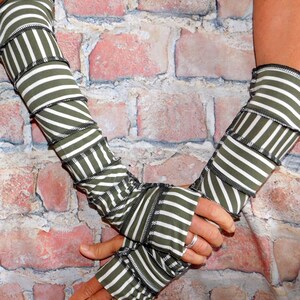 May include: A pair of long, striped arm warmers in green and white with a gathered, ruffled look. The arm warmers are made of a soft, stretchy fabric and are perfect for adding a touch of style to any outfit.
