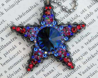 May include: A black star-shaped pendant necklace with red, blue, and clear rhinestones. The star has a large, dark blue crystal in the center.