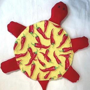 May include: A plush turtle toy with a red body and limbs. The shell is yellow and covered in a pattern of red chili peppers. The turtle has two small black eyes.