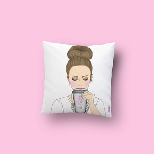May include: White throw pillow with a drawing of a woman with a bun in her hair, wearing a white shirt and a necklace, holding a coffee cup that says "Good Vibes, Badass, Coffee, Confidence, Dreams, Goals".