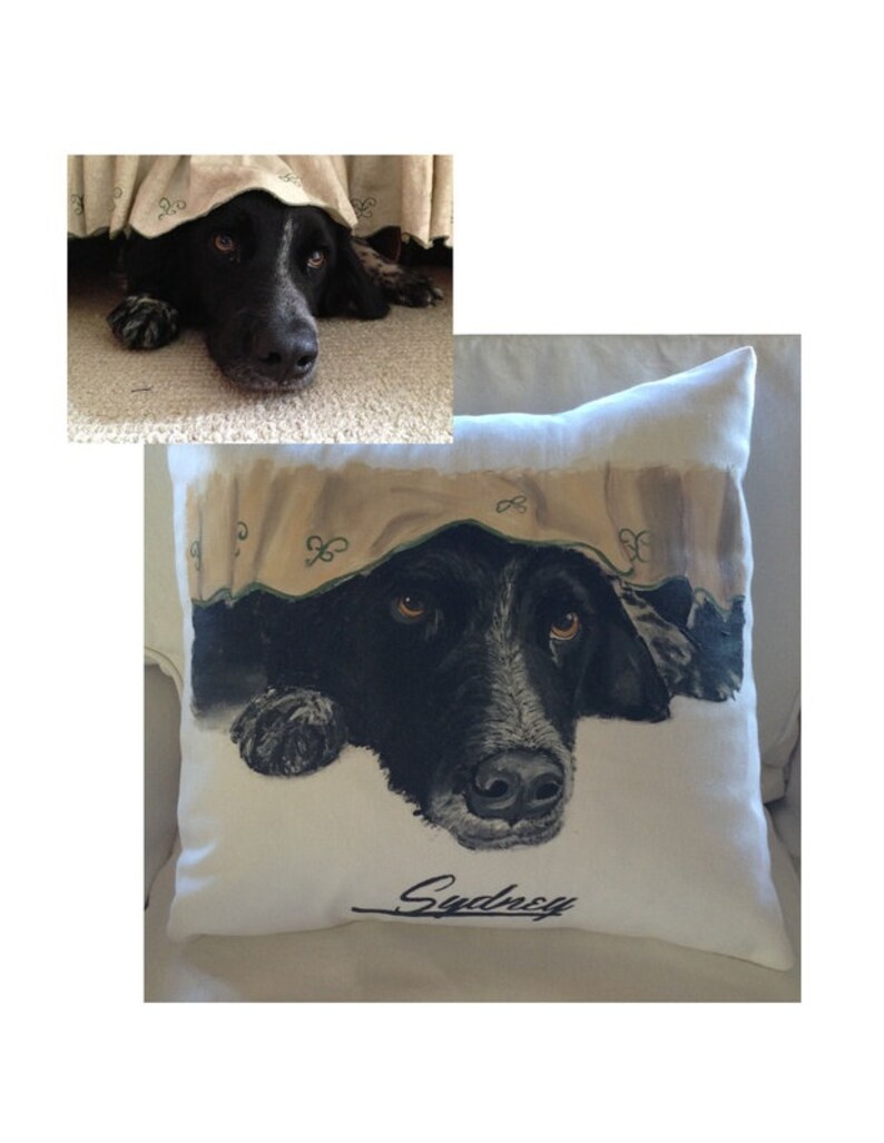 May include: A white pillow with a black and white illustration of a dog peeking out from under a blanket. The dog's name, "Sydney", is written in cursive at the bottom of the pillow.