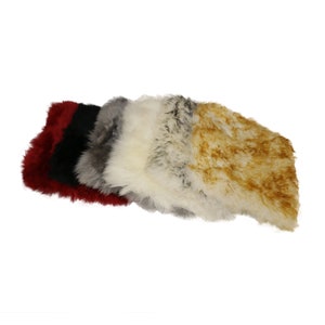 May include: Five sheepskin rugs in different colors, including red, black, gray, white, and tan. The rugs are stacked on top of each other, with the red rug on the bottom and the tan rug on the top.