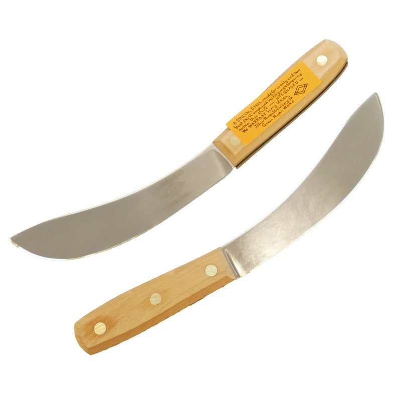 K&ouml;nnte beinhalten: Zwei gebogene Messer aus rostfreiem Stahl mit Holzgriffen. Die Griffe sind hellbraun und haben Messingnieten. Die Messer haben eine leichte Klingenkr&uuml;mmung und sind scharf. Das obere Messer hat ein gelbes Etikett mit dem Text "A SPECIAL STRES, mady for an only and ser We WARRANT very ads Green Rover - "