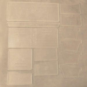 May include: A clear plastic template for leather crafting, with various shapes and sizes marked out. The template is labeled with numbers and letters.