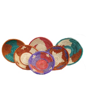 May include: Six round woven baskets with colorful patterns in shades of brown, red, blue, white, and teal. The baskets are arranged in a semi-circle.