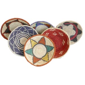 May include: Six woven baskets with colorful geometric designs. The baskets are made of natural materials and have a round shape.