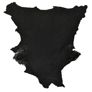 May include: A black leather hide with a rough, textured surface. The hide has an irregular shape with a jagged edge.