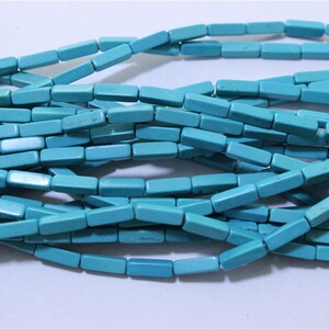 May include: A strand of turquoise blue rectangular beads. The beads are smooth and polished, and they have a slightly irregular shape.