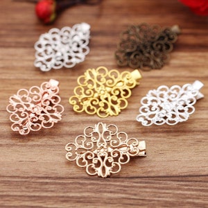 May include: Six decorative hair clips in different colours, including gold, silver, and rose gold. Each clip features a delicate, intricate design with a diamond shape.