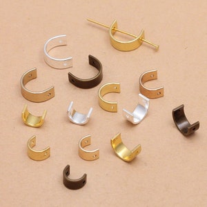 May include: Assortment of metal jump rings in various finishes, including gold, silver, and bronze. The jump rings are all in the shape of a half-circle and have two small holes on either side.