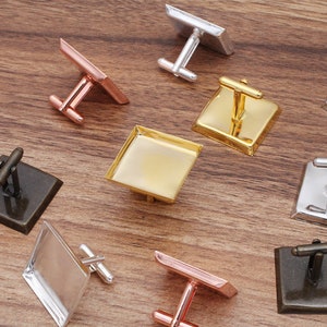 Puede incluir: Un juego de seis gemelos con inserciones de vidrio de forma cuadrada. Los gemelos están hechos de diferentes metales, incluyendo oro, plata y bronce. Las inserciones de vidrio son transparentes y tienen una superficie lisa.