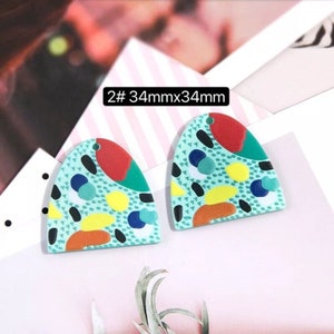 May include: Two 34mm x 34mm resin earrings with a geometric pattern in shades of green, yellow, red, orange, and black.
