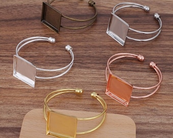 Puede incluir: Cinco pulseras de metal de diferentes colores con inserciones de vidrio cuadradas. Las pulseras son de plata, oro, oro rosa y bronce.