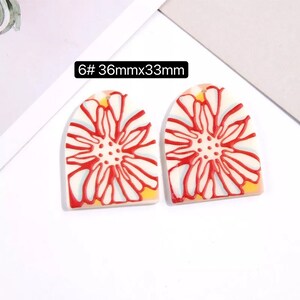 May include: A pair of white ceramic earrings with a red floral design. The earrings are shaped like an arch and measure 36mm x 33mm. 6# 36mmx33mm