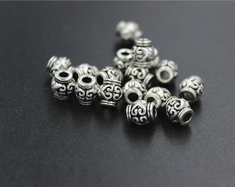 May include: A collection of silver metal beads with intricate designs. The beads are round and have a hole in the centre. They are ideal for jewellery making or other craft projects.