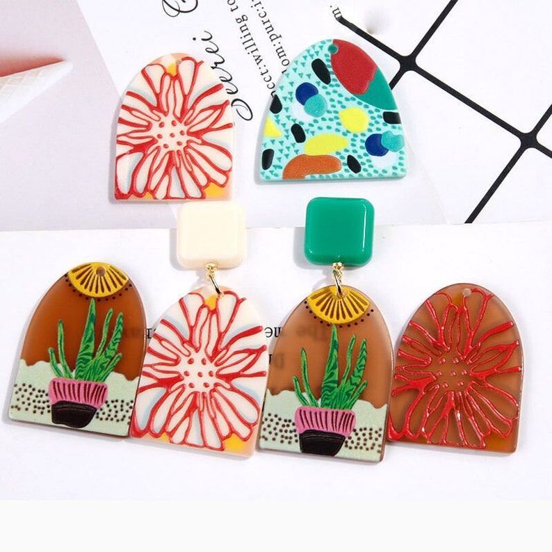 May include: A set of six colorful, geometric earrings. The earrings are made of resin and feature a variety of designs, including flowers, plants, and abstract patterns. The earrings are perfect for adding a touch of whimsy to any outfit.