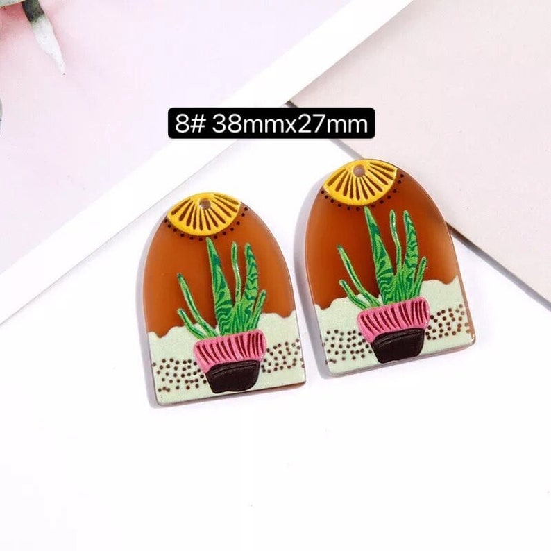 May include: Two brown, arched, resin earrings with a green succulent plant design. The earrings are 38mm x 27mm.