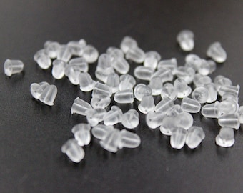 May include: A pile of clear plastic earring backs. The backs are small and round, with a small hole in the centre. They are designed to be used with stud earrings.