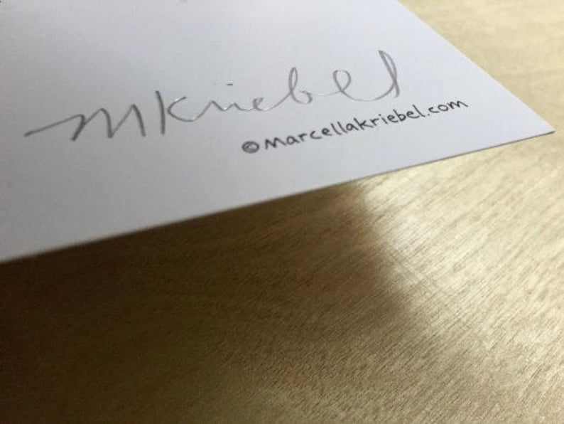 May include: A white card with the signature "M. Kriegel" and the website "marcellakriegel.com" printed in silver.