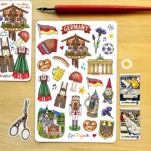 May include: A sticker sheet featuring various German-themed illustrations including a cuckoo clock, the Brandenburg Gate, a nutcracker, a pretzel, a beer stein, a sausage, a dirndl, lederhosen, a soccer ball, and the German flag with the text GERMANY.