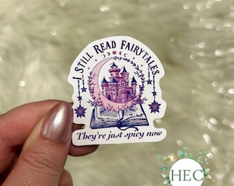 May include: A white sticker with a purple castle inside a crescent moon with stars and a book below. The text reads "I still read fairytales they're just spicy now".