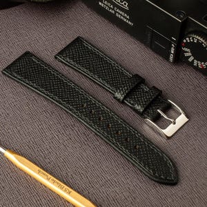 May include: Two black leather watch straps with a silver buckle. The straps have a textured grain pattern.