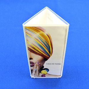 May include: Transparent plastic 1/3rd A4 holder with a triangular top. The holder features a colourful image of a person with vibrant, striped hair. The text "1/3rd A4 Holder" is visible on the front.