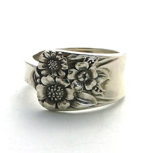 May include: A silver ring with a floral design. The ring is made from a repurposed spoon.