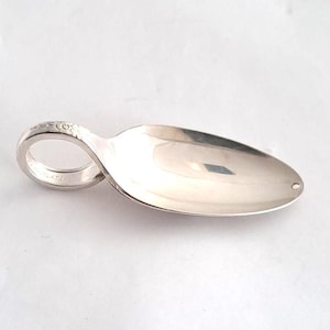 May include: A silver spoon with a loop handle and a small, oval bowl. The handle features a floral design. The spoon is made of a shiny, reflective metal, likely silver-plated. The spoon is designed for serving or eating.