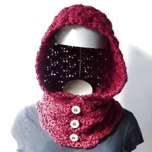 May include: A burgundy crocheted hooded cowl with three white buttons.
