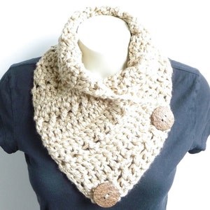 May include: A beige crocheted cowl neck scarf with two brown wooden buttons.