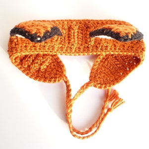May include: Orange crocheted headband with black ears. The headband has a long tie that can be tied under the chin.