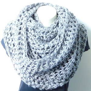 May include: A gray crocheted infinity scarf with a delicate openwork pattern. The scarf is draped over a mannequin's neck.