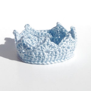 May include: A light blue crocheted crown with a pointed top and five points.