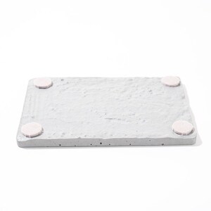 Peut inclure: Un plateau rectangulaire en b&eacute;ton gris avec quatre patins en feutre blanc sur le dessous.