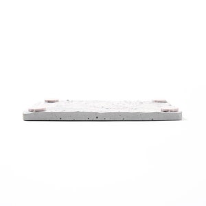 Peut inclure: Un dessous de verre carr&eacute; en b&eacute;ton avec une surface rugueuse et textur&eacute;e. Le dessous de verre a quatre petits pieds en caoutchouc rose sur le dessous.